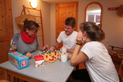 un hombre y dos mujeres sentados en una mesa jugando ajedrez en Ferienwohnung Spatzennest en Frankenberg