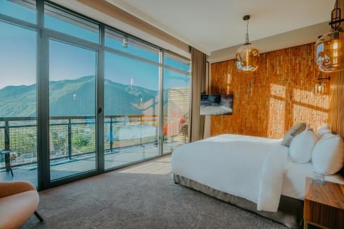 a bedroom with a white bed and a large window at Mtserlebi Resort in K'vishkhet'i