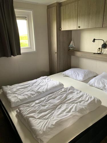 two unmade beds in a bedroom with a window at Luxe Chalet dichtbij Zoutelande in Biggekerke