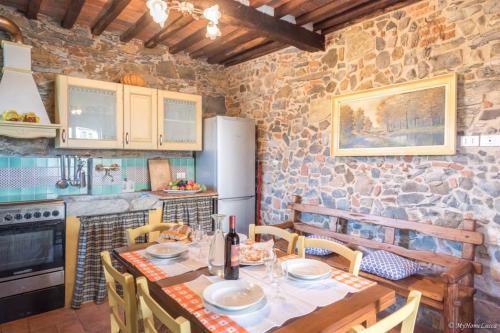 cocina con mesa, sillas y pared de piedra en Alla Bella Aurora with Amazing POOL in Tuscany, en Lucca