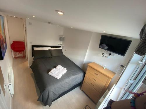 a small bedroom with a bed and a flat screen tv at Comfortable cosy double ensuite room 'Karibu' in Cherry Hinton