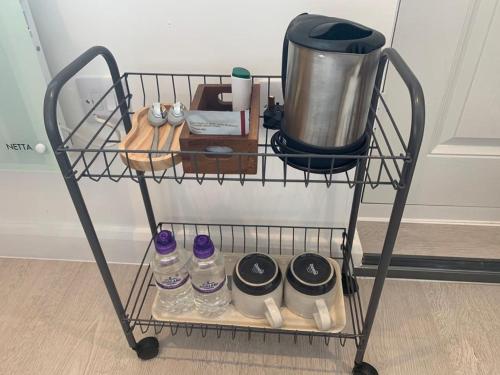 a wire shelf with bottles of water and a blender at Comfortable cosy double ensuite room 'Karibu' in Cherry Hinton