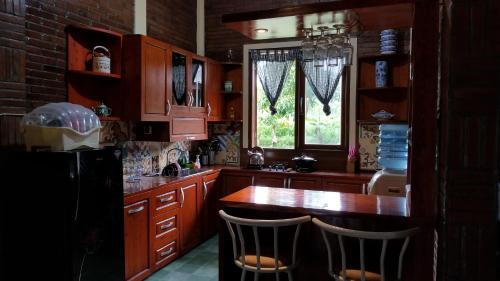 a kitchen with wooden cabinets and a kitchen island with chairs at Villa Joglo Cimande in Bogor