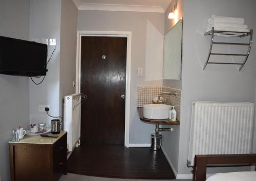 a room with a bathroom with a door and a sink at Middle Farm Villa B&B in Wellingborough