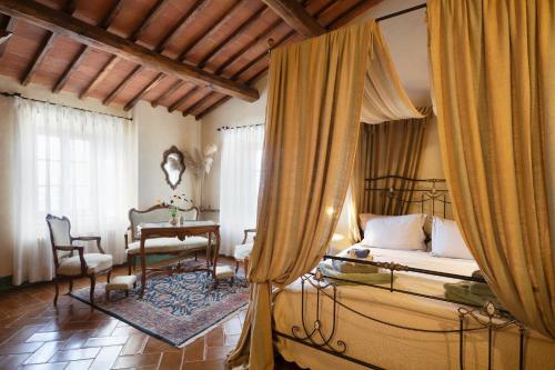 a bedroom with a canopy bed and a table and chairs at Villa Montecastello in Monteriggioni
