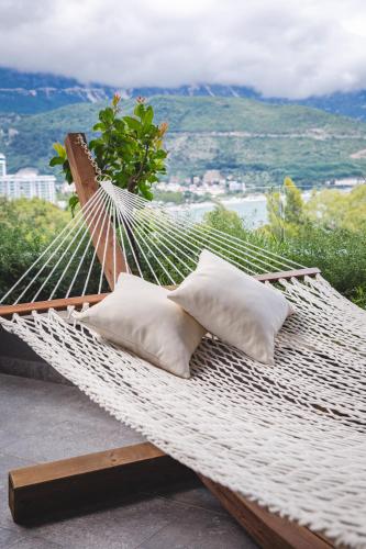 a hammock with pillows on a balcony with a view at Boutique Hotel Vissi d'Arte in Budva