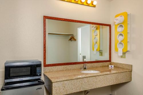 y baño con microondas y lavabo con espejo. en Motel 6 Oakdale, Ca, en Oakdale