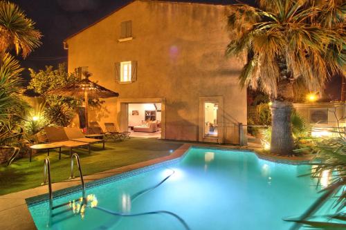 - une piscine en face d'une maison la nuit dans l'établissement Maison avec piscine et jardin- 4 chambres 8 pers, à Cuers