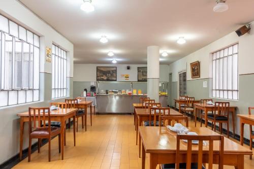 a restaurant with wooden tables and chairs and a kitchen at Hotel Esplanada Belo Horizonte - Proximo a Estacao de Trem in Belo Horizonte