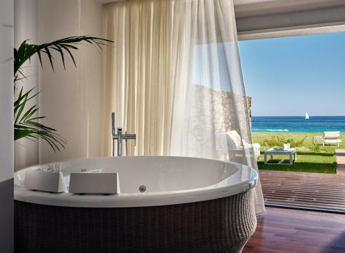 a bath tub in a bathroom with a view of the ocean at Lesante Blu, a member of The Leading Hotels of the World - Adults Only in Tragaki
