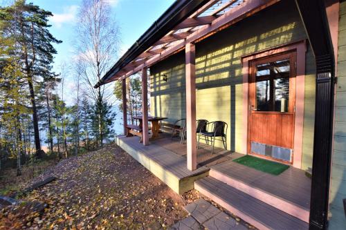 a front porch of a house with a table and chairs at Pyhtään Vuokramökit in Tuuski