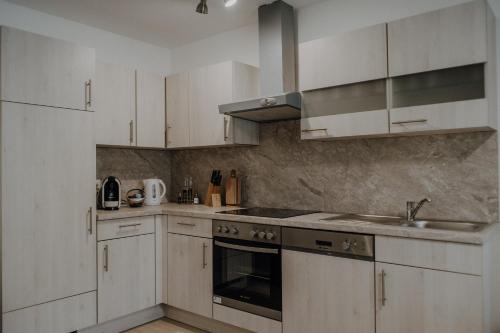 uma cozinha com armários brancos, um lavatório e um fogão em Peter Lamster Top2 em Frauenkirchen