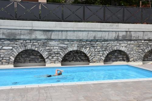 a person in a swimming pool in a stone wall at Casa Julia - Menaggio by LoveComo in Menaggio