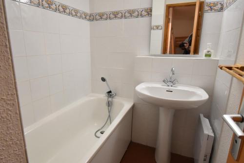 une salle de bain blanche avec un lavabo et une baignoire dans l'établissement VAUJANYLOCATIONS - Cochette I Apt 14, à Vaujany