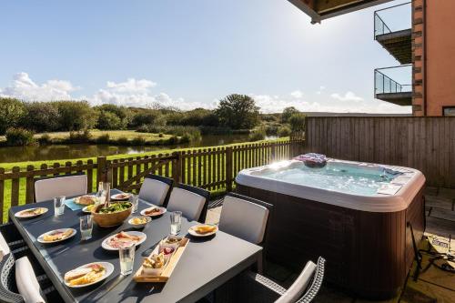 a patio with a table and a hot tub at Retallack Resort by Away Resorts in Padstow