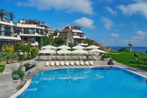 a swimming pool with white umbrellas and a building at Art Complex Anel in Sozopol