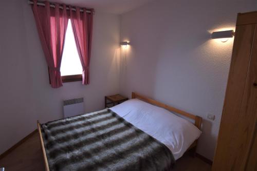 une petite chambre avec un lit et une fenêtre dans l'établissement VAUJANYLOCATIONS - Cochette I Apt 14, à Vaujany