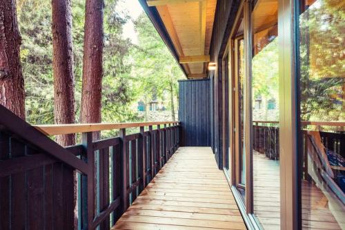 un porche de madera de una casa con árboles en ClamLive Lodge, en Klam
