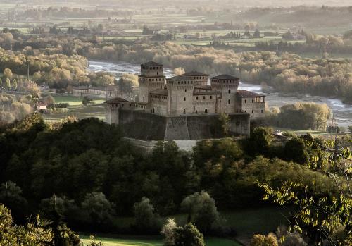 a castle on top of a hill with trees at La Locanda del Borgo in Torrechiara
