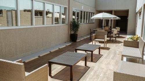 a patio with tables and chairs and an umbrella at Annaya Suítes in Viçosa