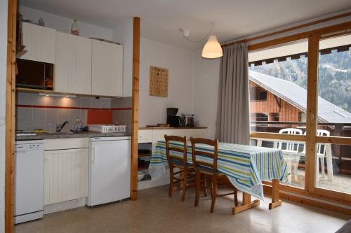 une cuisine et une salle à manger avec une table et des chaises dans l'établissement VAUJANYLOCATIONS - La Fare Apt 10, à Vaujany