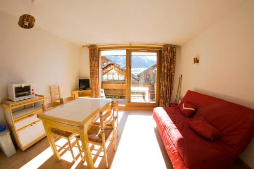 a living room with a red couch and a table at VAUJANYLOCATIONS - Claret II Studio 3 in Vaujany