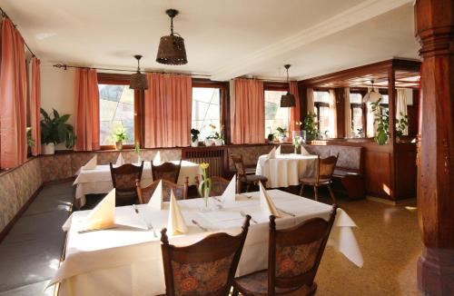 un restaurante con mesas y sillas blancas y ventanas en Landgasthof Sonne en Mainhardt