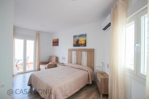 - une chambre avec un lit, une chaise et des fenêtres dans l'établissement Casa Jupiter, à Conil de la Frontera