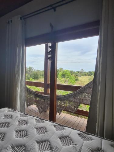 um quarto com vista para uma rede de descanso a partir de uma janela em Taipu Beach House - Barra Grande em Barra Grande