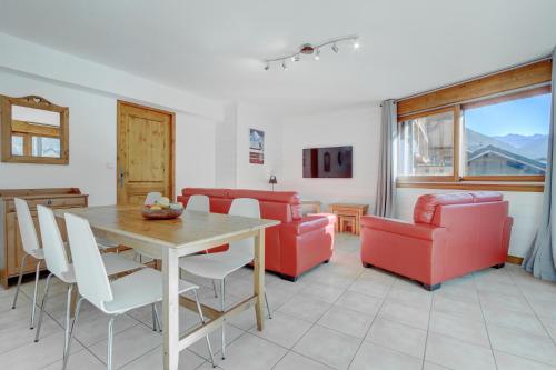 a living room with a table and red chairs at Slalom Apartment - Very Town Centre - Snow and Trek - Morzine in Morzine