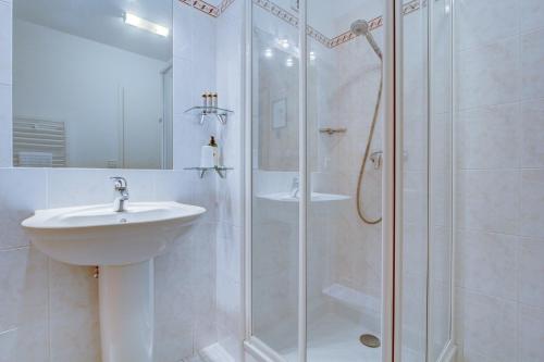 une salle de bain blanche avec une douche et un lavabo dans l'établissement Chalet Madeleine - Snow and Trek, à Morzine