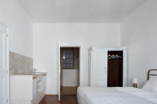 a white bedroom with a bed and a desk at Stará Pekárna/Old Bakery in Znojmo