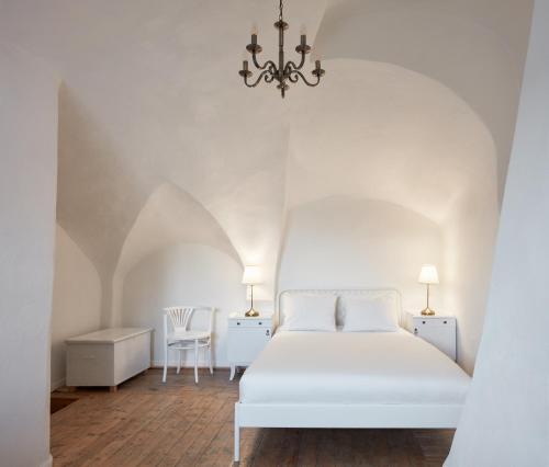 a white bedroom with a white bed and a chandelier at Stará Pekárna/Old Bakery in Znojmo