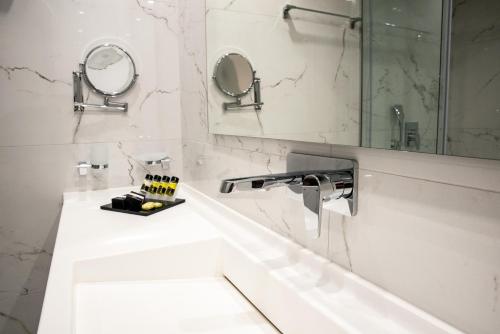a white bathroom with a sink and a mirror at Lagaria Hotel in Afitos