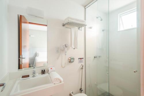 a bathroom with a shower and a sink and a toilet at Hotel Melo in Balneário Camboriú