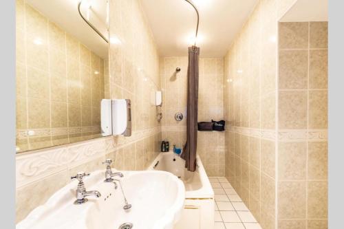 uma casa de banho com um lavatório, um espelho e uma banheira em OYO Paddington House Hotel em Warrington