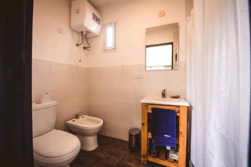 a bathroom with a toilet and a sink and a window at Tiny House Necochea in Necochea