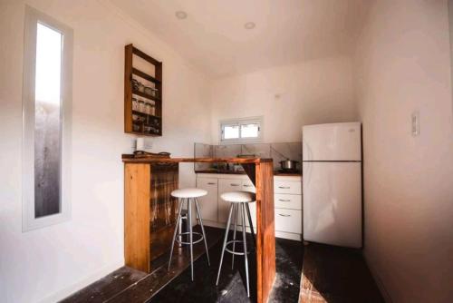 a kitchen with two stools and a refrigerator at Tiny House Necochea in Necochea
