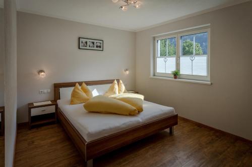 ein Schlafzimmer mit einem Bett mit Kissen und einem Fenster in der Unterkunft Appartements KATHARINA in Aschau