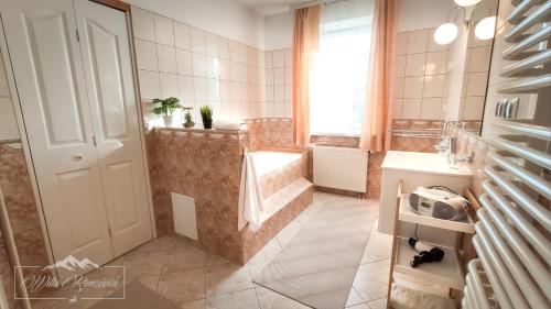 a bathroom with a sink and a tub and a toilet at Willa Ramzówka - Dom z Bilardem, Sauną i Jacuzzi in Nowy Sącz