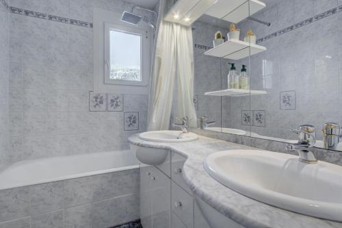 une salle de bain blanche avec un lavabo et une baignoire dans l'établissement Le Pleney Apartment - Snow and Trek, à Morzine