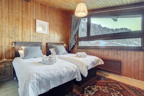 deux lits dans une chambre avec une fenêtre dans l'établissement Le Pleney Apartment - Snow and Trek, à Morzine