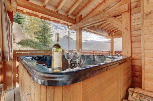 モルジヌにあるRose et Chardon Apartment - Snow and Trek - Morzineのワインのボトルとグラスが置かれた丸太小屋のバー