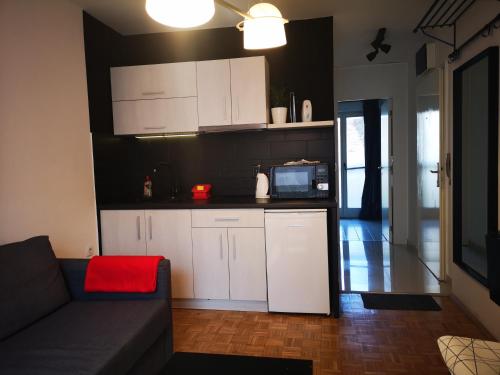 a kitchen with white cabinets and a couch in a room at FilinHome Teleckog in Novi Sad