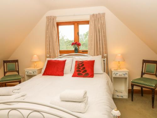 a bedroom with a white bed with red pillows at Granary Cottage in Shipston-on-Stour