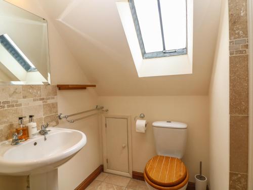 baño con lavabo y aseo y ventana en Granary Cottage, en Shipston on Stour