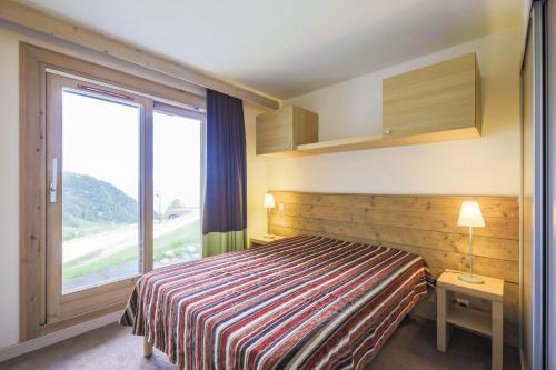 une chambre d'hôtel avec un lit et une grande fenêtre dans l'établissement Residence Les Gemeaux - maeva Home, à Belle Plagne