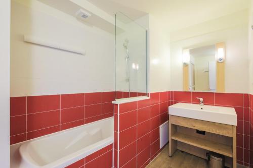La salle de bains est pourvue de carrelage rouge, d'un lavabo et d'une baignoire. dans l'établissement Residence Les Gemeaux - maeva Home, à Belle Plagne