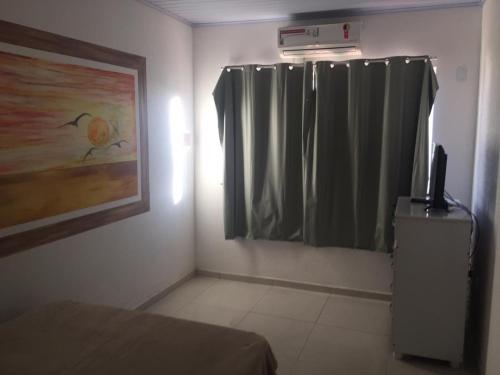 1 dormitorio con 1 cama y una ventana con cortinas en Suítes Centro, en Arraial do Cabo