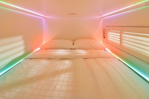 a small room with a bed with pink lights at CityHub Copenhagen in Copenhagen